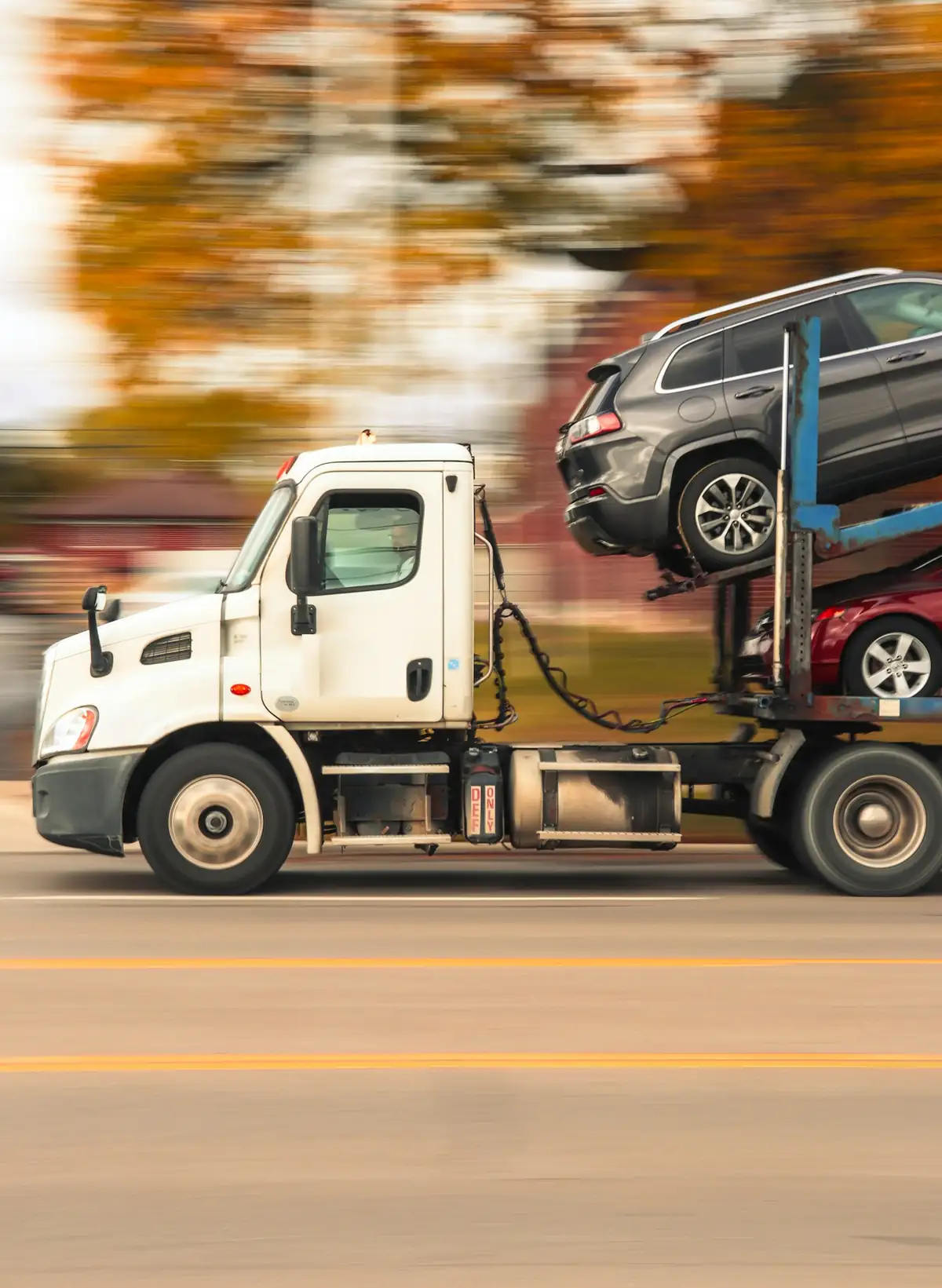 A car hauler on the road with an SUV on the top deck and a sedan below